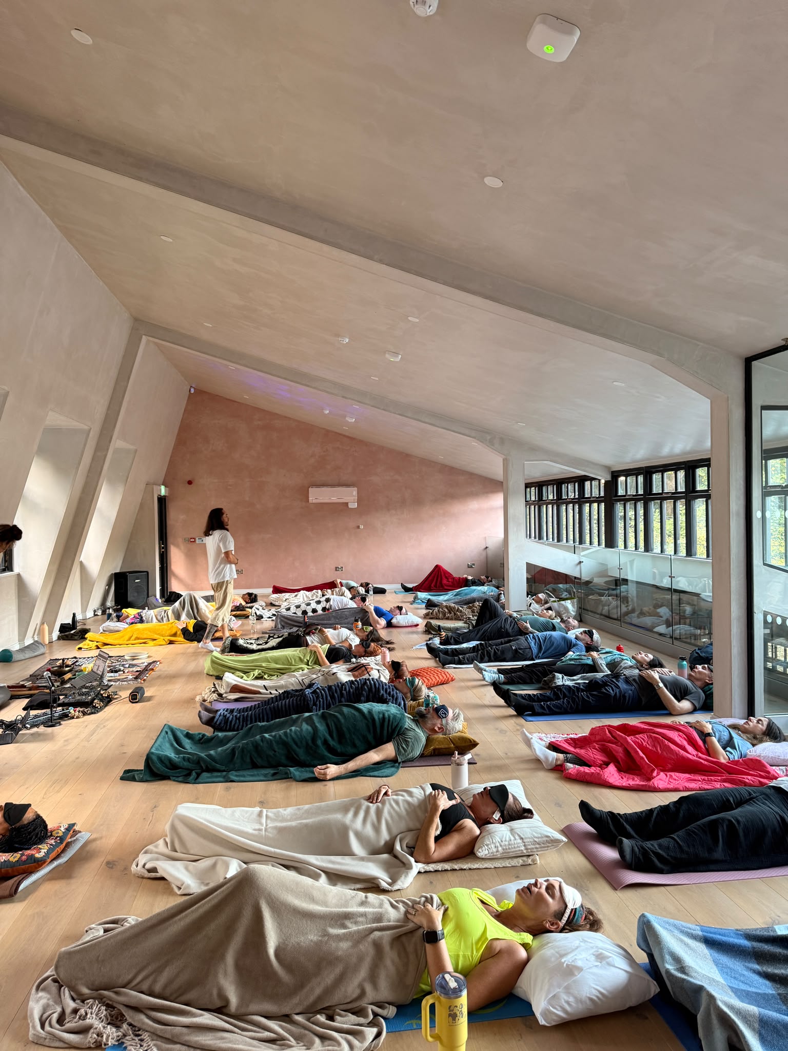 Matt guiding a group breathwork session, participants lying on mats under blankets